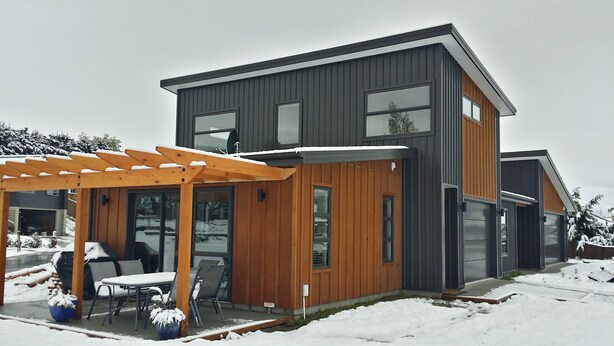 A modern two-story house with a covered patio area.