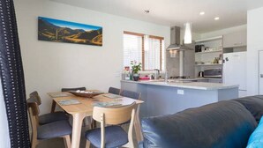 A modern kitchen with a central island, dining table with chairs, and a living area with a sofa.