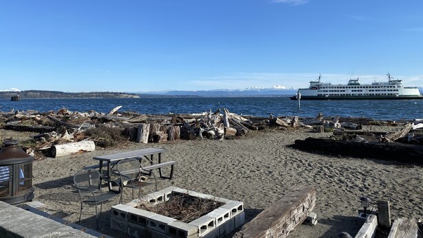 Une plage avec une structure en bois, une table et des chaises.