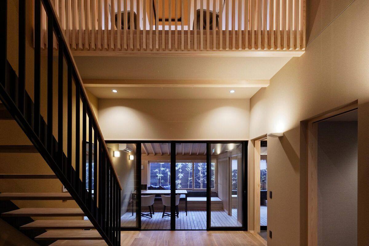 Ein modernes Interieur mit einer Holztreppe, einem Essbereich und Blick durch Glastüren.