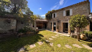 Un edificio de piedra con un patio, escalones de piedra y un árbol.