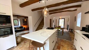 Una cocina con isla central, armarios blancos y vigas de madera a la vista.