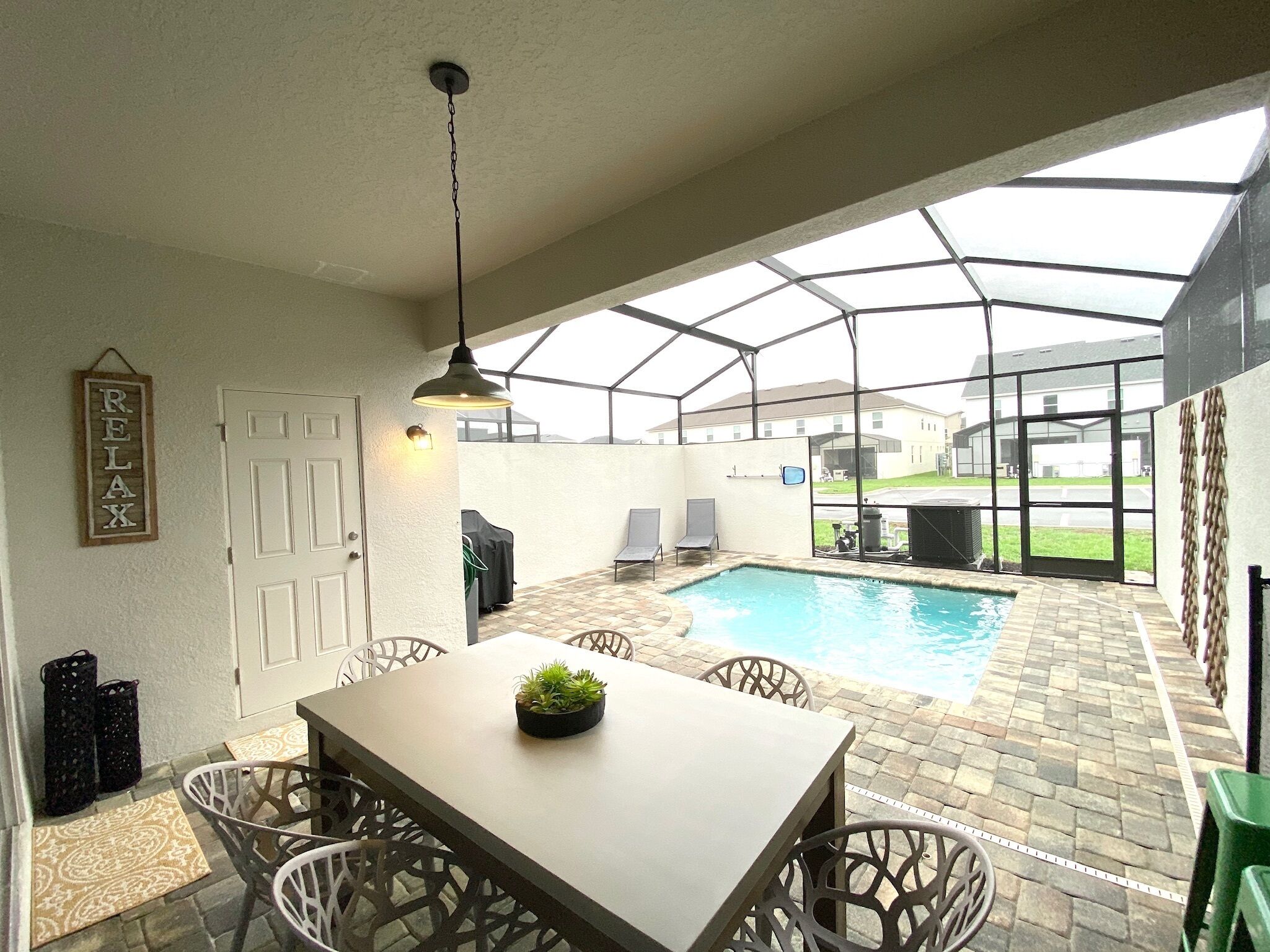 A covered patio with a pool, a table with chairs, and a 'RELAX' sign on the wall.