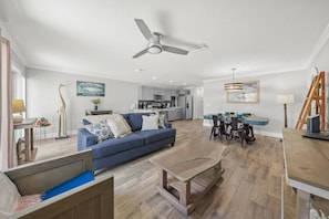 Un salon moderne avec un canapé bleu, une table basse en bois et un coin repas comprenant une table et des chaises bleues.