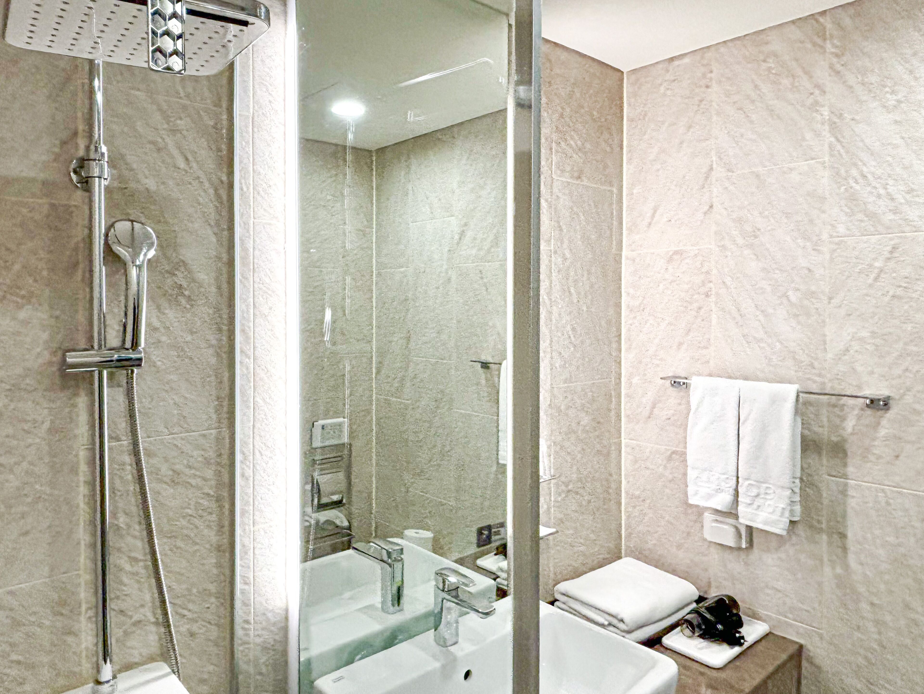 A modern bathroom with a glass-enclosed shower, a sink, and a toilet.