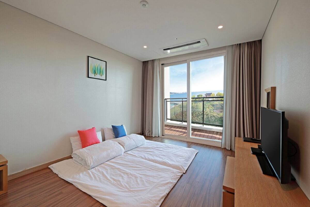 A hotel room with a large bed, a flat-screen TV, and a balcony with a view.