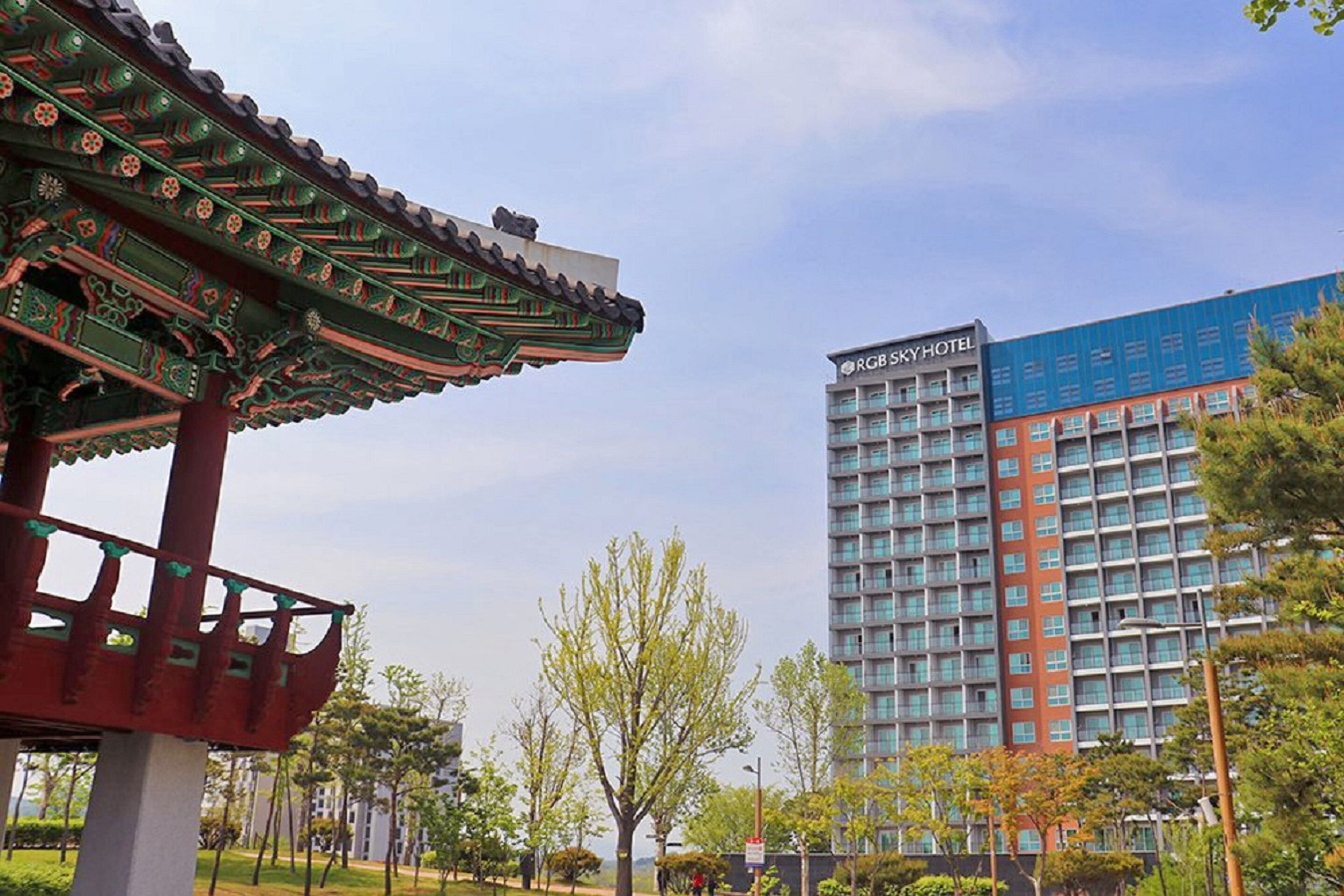 A traditional Korean pavilion with a modern hotel in the background.