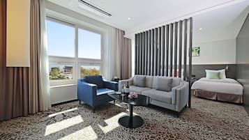 A hotel room with a sofa, a chair, a coffee table, and a bed.