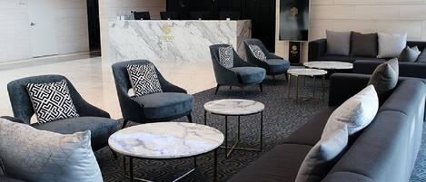 A modern lobby with a reception desk, seating area, and a large screen.