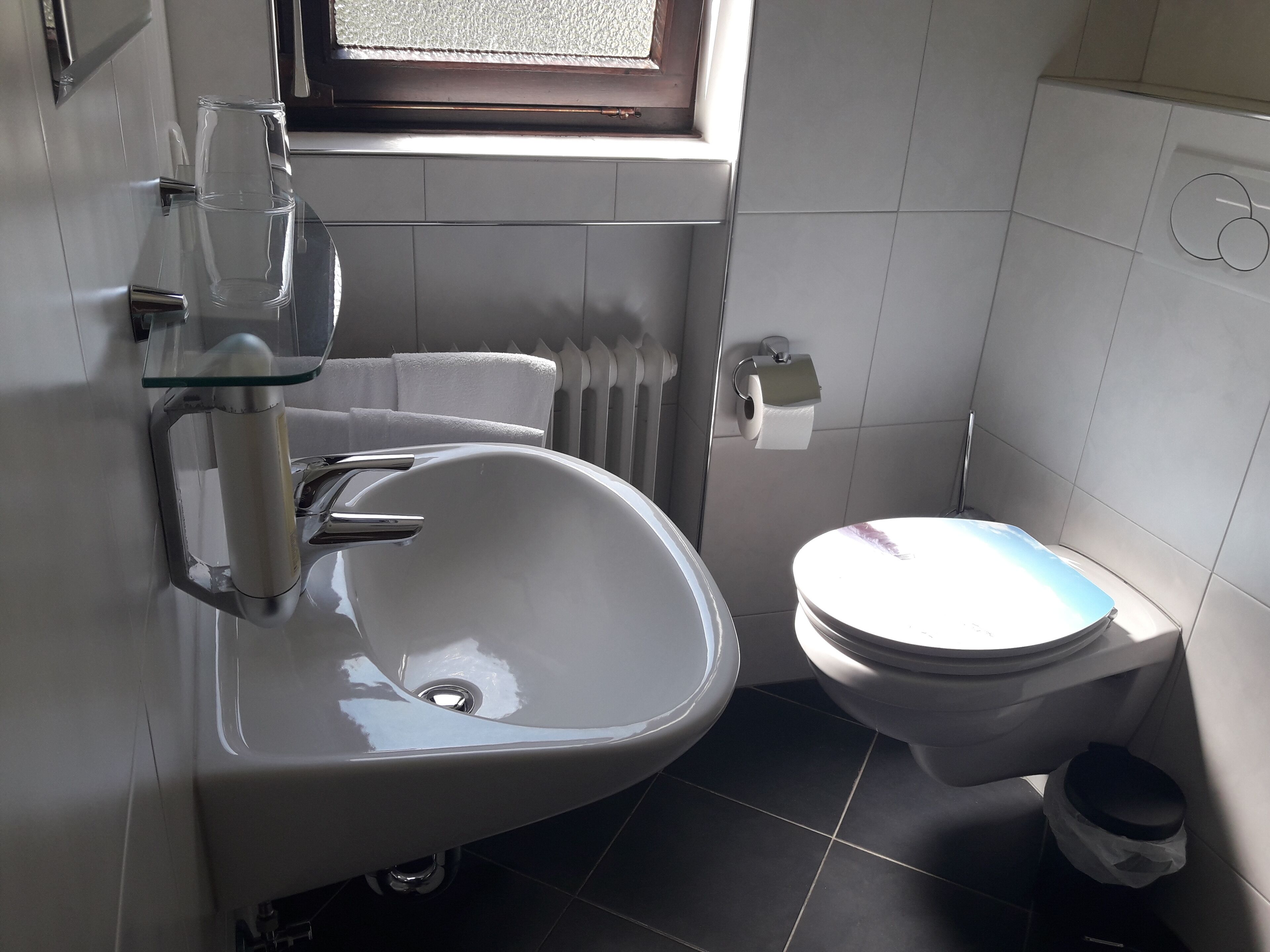 Ein Badezimmer mit Waschbecken, Toilette und einem Fenster über dem Waschbecken.