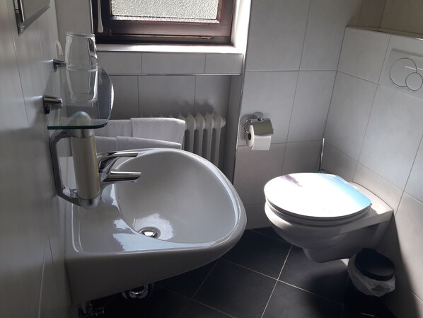 Ein Badezimmer mit Waschbecken, Toilette und einem Fenster über dem Waschbecken.