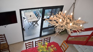 Ein Essbereich mit einem für zwei Personen gedeckten Tisch, einer Chandelüster und einem an der Wand befestigten Fernseher.
