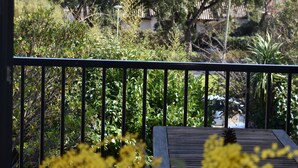 Ein Balkon mit Blick auf einen Garten und Bäume.