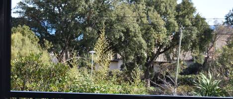 A balcony with a view of a garden and trees.