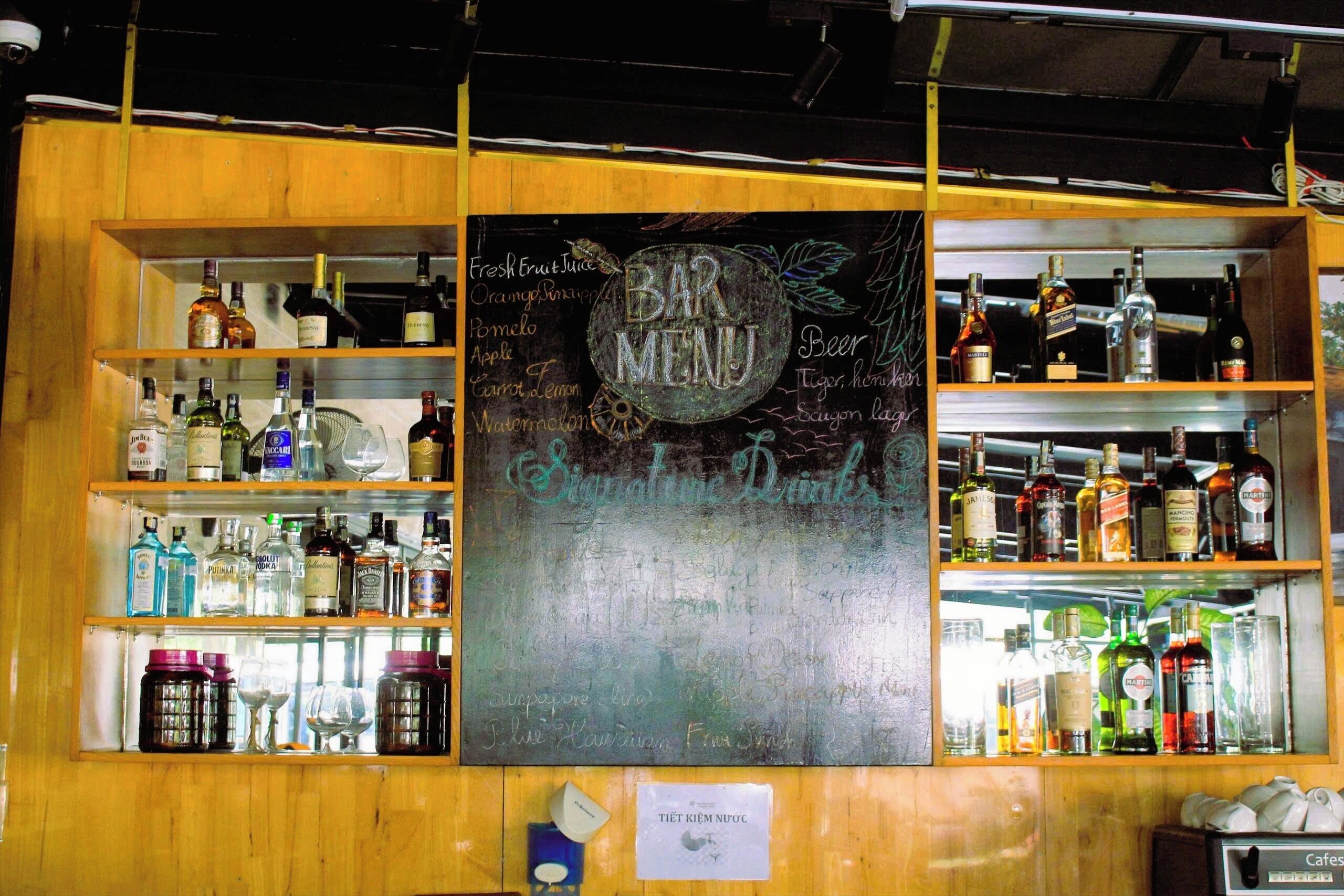 A bar with a chalkboard menu listing various drinks and a sign for signature drinks.
