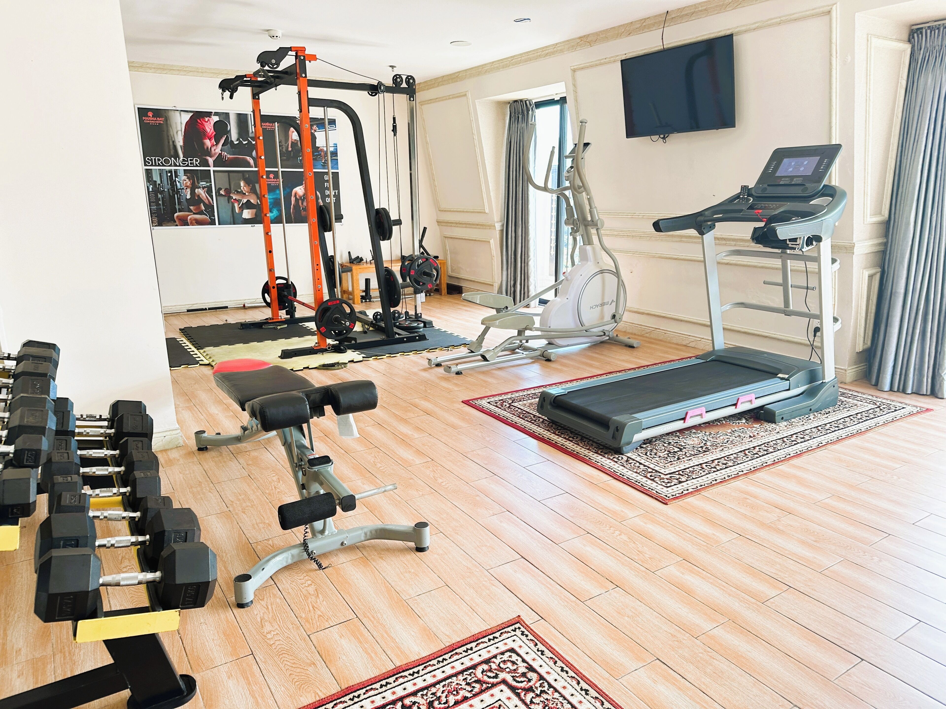 Une salle de sport à domicile équipée d’un tapis de course, d’un banc de musculation, d’haltères et de divers appareils d’exercice.