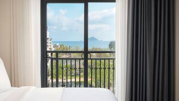 Habitación de hotel con cama, vista al mar y balcón con barandilla.