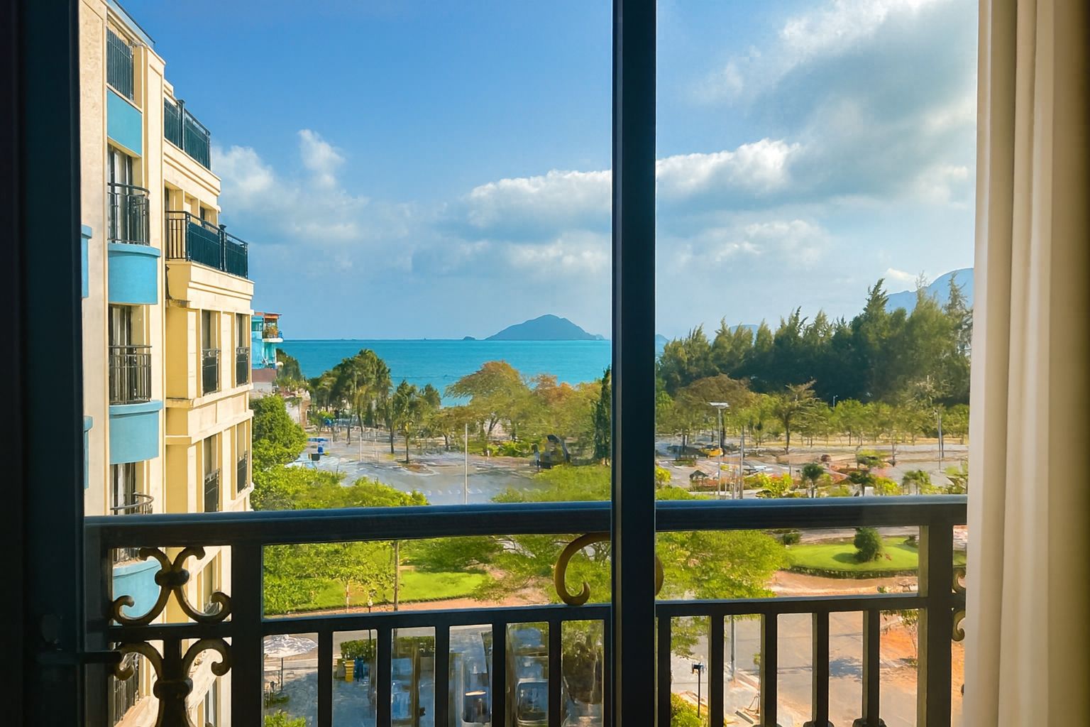 A balcony with a view of a coastal area, including a body of water and distant mountains.