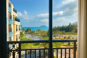 A balcony with a view of a coastal area, including a body of water and distant mountains.