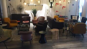 Ein stilvoller Lounge-Bereich mit verschiedenen Sitzmöglichkeiten, einem Klavier und dekorativer Wandgestaltung.