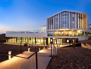 Ein modernes Hotel mit Glasfassade, Außenbereich und Poolanlage.