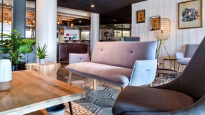 A modern interior with seating, a wooden table, and a patterned floor.