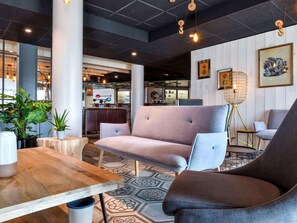 Ein modernes Interieur mit Sitzgelegenheiten, einem Holztisch und einem gemusterten Boden.