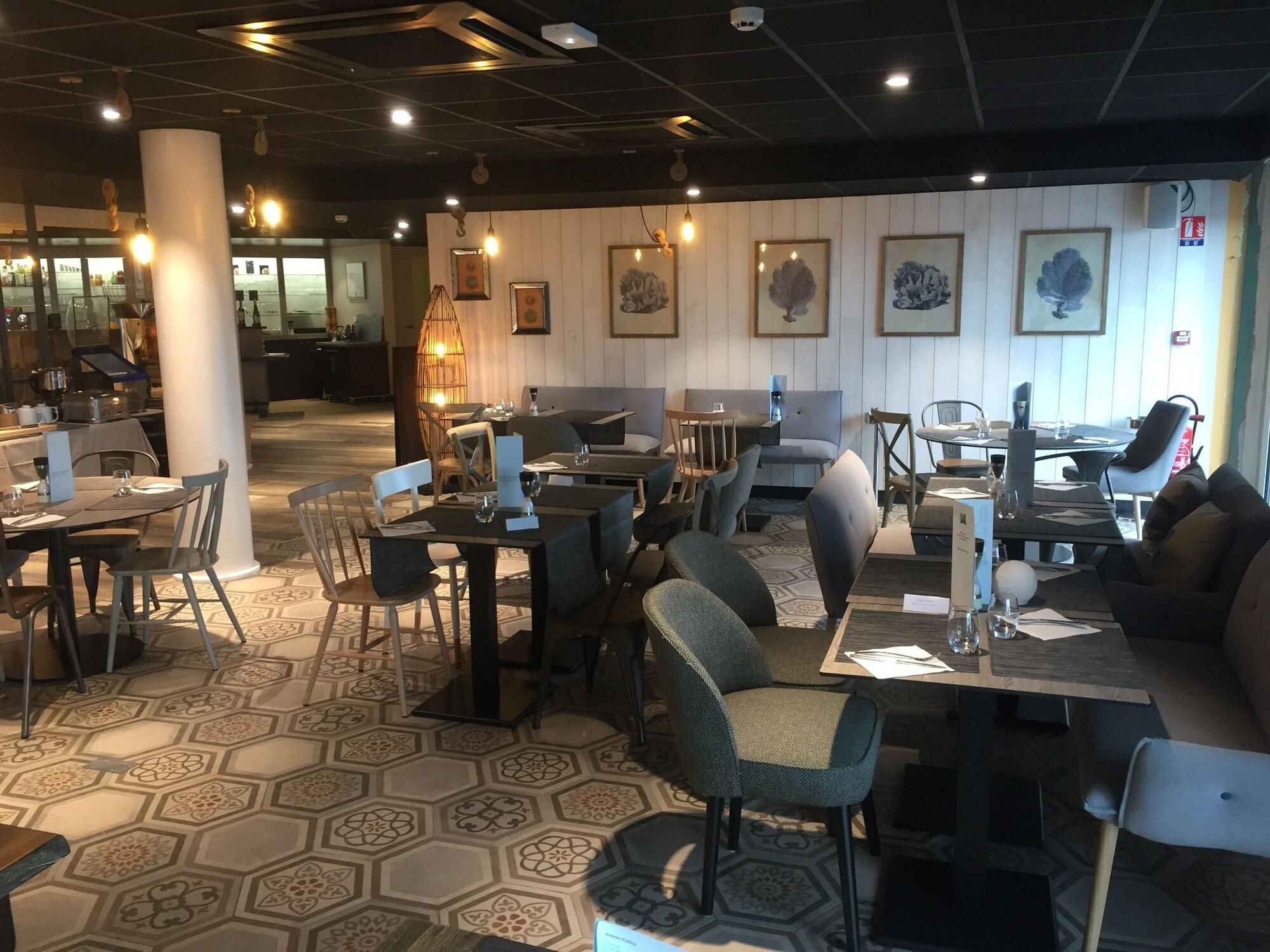 Ein Restaurant mit sechseckigem Fliesenspiegel, Tischen und Stühlen sowie gerahmten Kunstwerken an den Wänden.