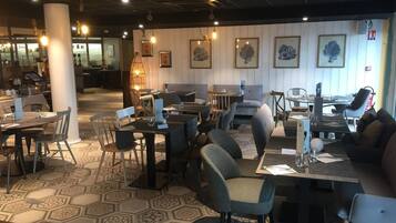Ein Restaurant mit sechseckigem Fliesenspiegel, Tischen und Stühlen sowie gerahmten Kunstwerken an den Wänden.