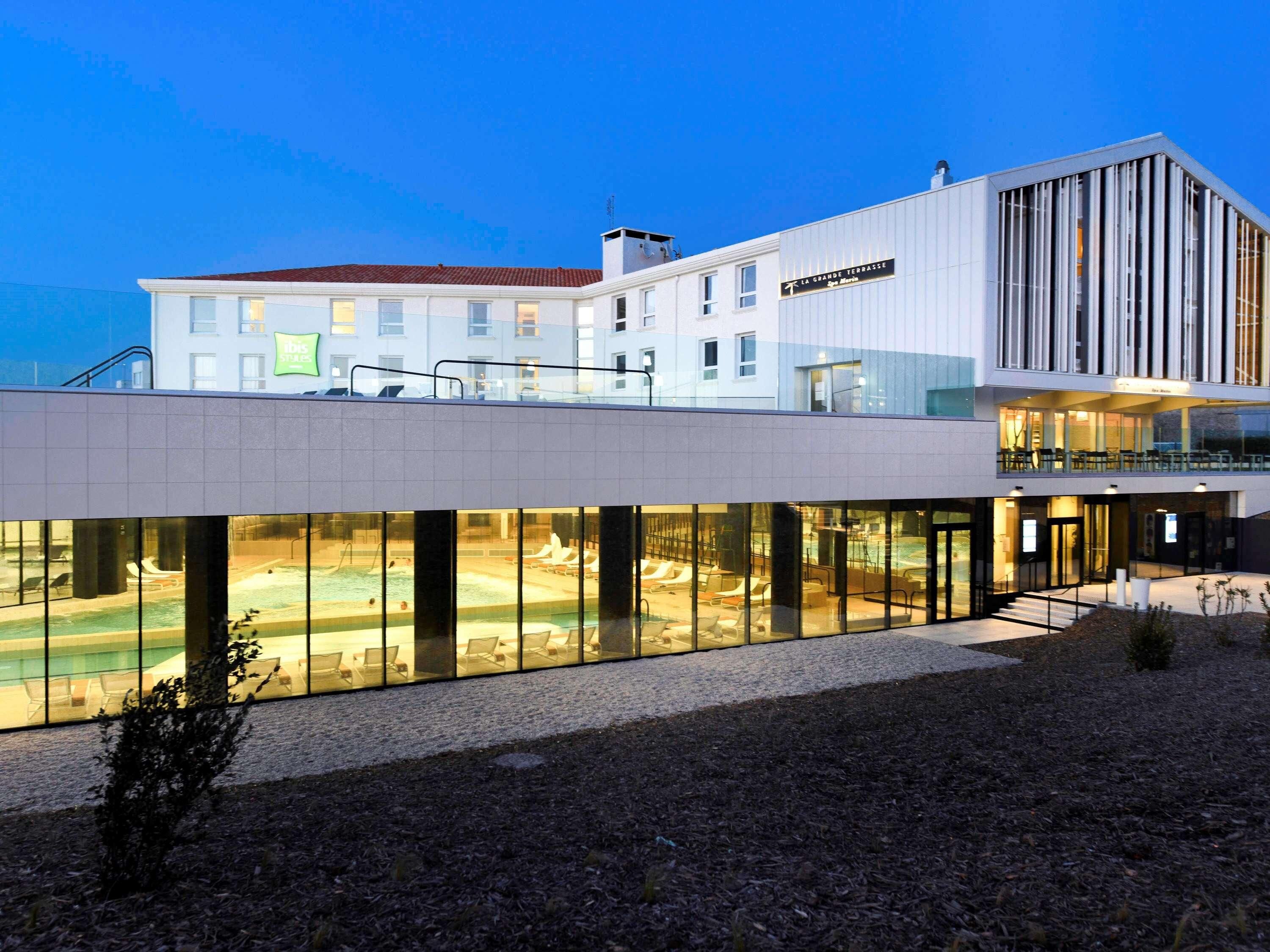 Un hotel modern amb zona de piscina, terrassa i restaurant.