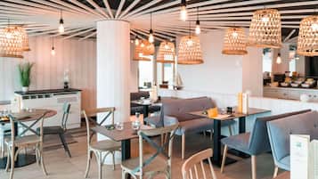 Interior modern d'un restaurant amb moble de fusta, il·luminació penjant i un suport de menú visible.