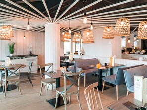 A modern restaurant interior with wooden furniture, pendant lighting, and a visible menu stand. - Ibis Styles La Rochelle Thalasso Chatelaillon (Chatelaillon-Plage)