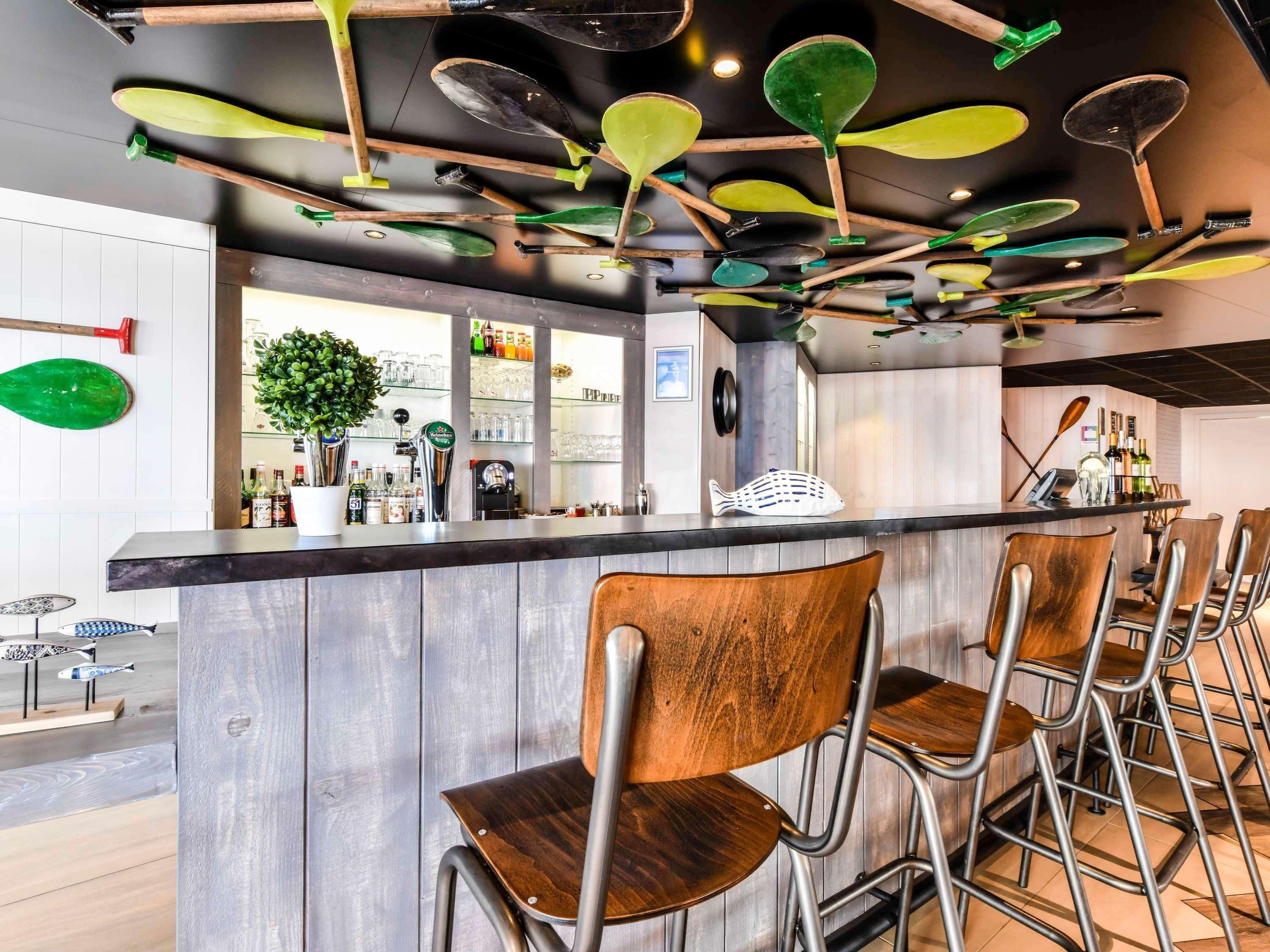 Angolo bar con sedie in legno, un bancone con attrezzi da bar e una pianta.
