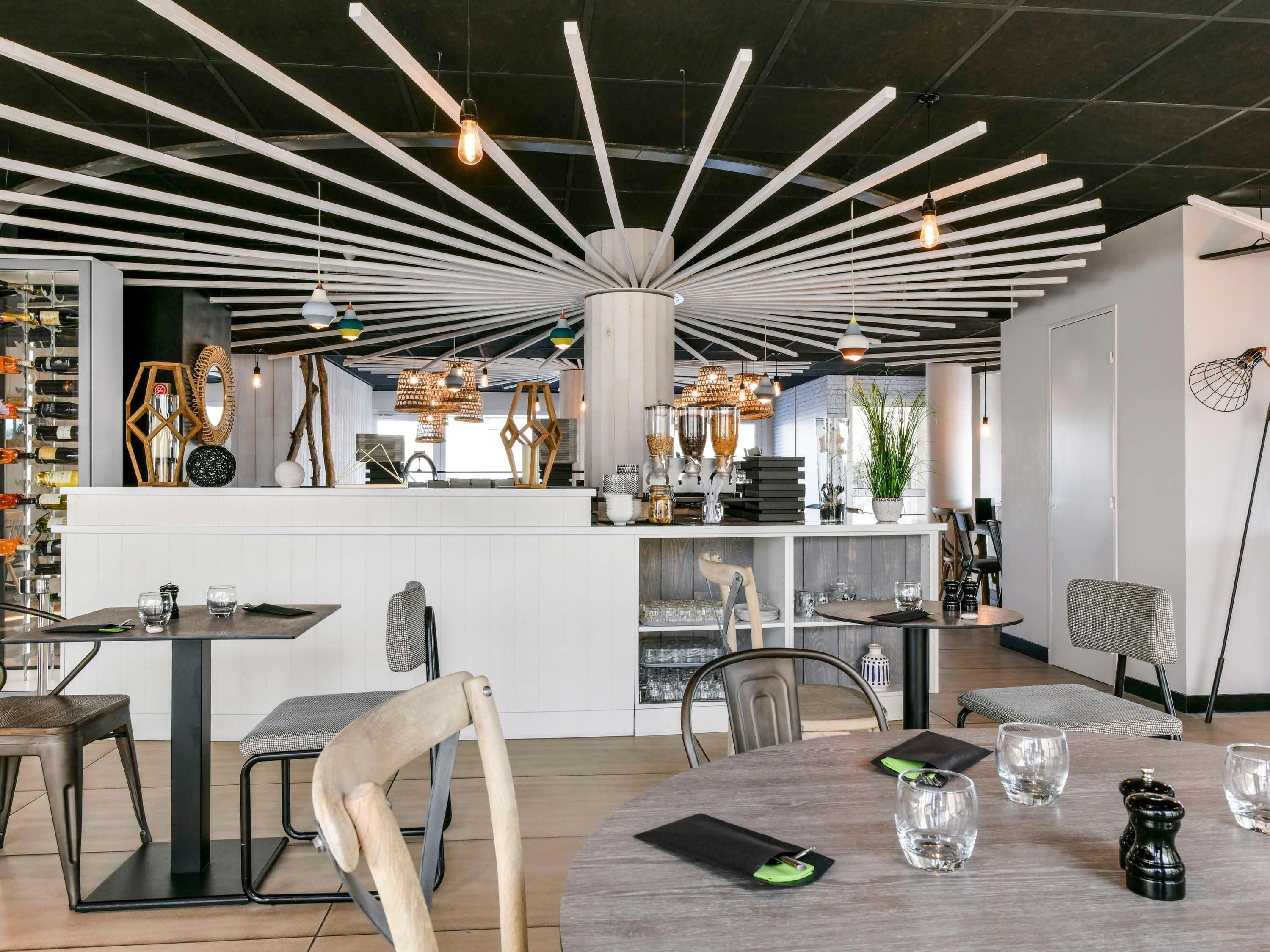 A modern interior with a central bar area, multiple seating arrangements, and a variety of lighting fixtures.