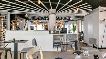 A modern interior with a central bar area, multiple seating arrangements, and a variety of lighting fixtures.