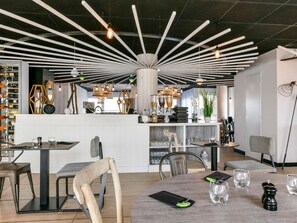 A modern interior with a central bar area, multiple seating arrangements, and a variety of lighting fixtures. - Ibis Styles La Rochelle Thalasso Chatelaillon (Chatelaillon-Plage)