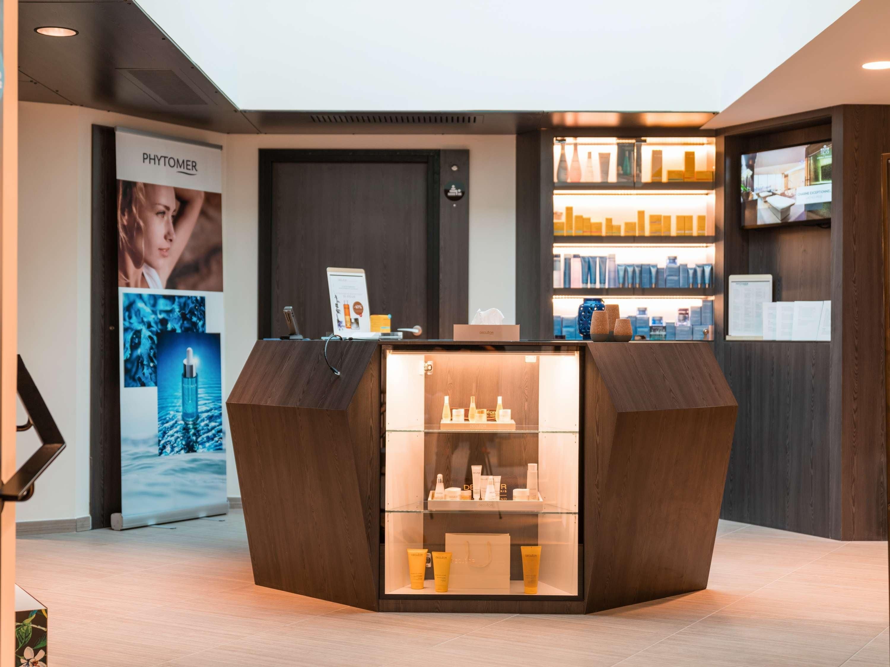 A reception desk with a glass display case, a digital screen, and a Phytomer advertisement.