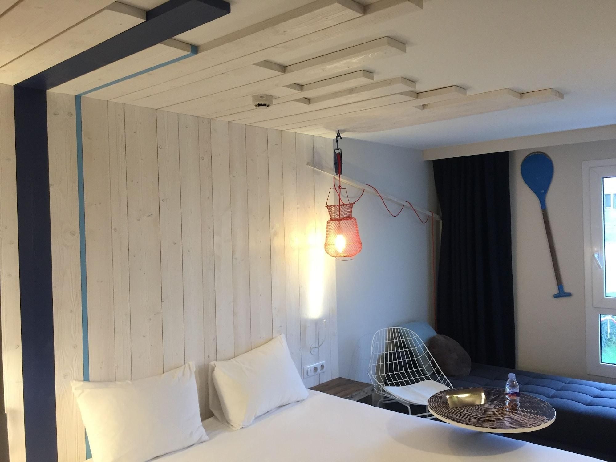 A room with a bed, a hanging light fixture, a paddle, and a window with curtains.