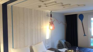 A room with a bed, a hanging light fixture, a paddle, and a window with curtains.
