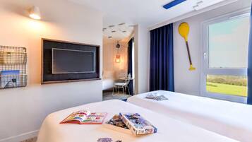 Habitación de hotel con cama, escritorio, silla, televisor y ventana con vistas.