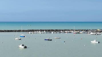 Un port esportiu amb diverses embarcacions amarrades, un moll de pedra i aigua tranquil·la.