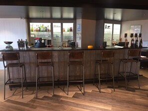 A bar area with a counter, stools, and a display of bottles. - Ibis Styles La Rochelle Thalasso Chatelaillon (Chatelaillon-Plage)