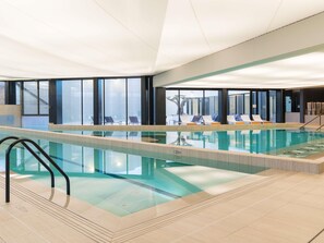 An indoor swimming pool with clear water, a diving board, and lounge chairs by the poolside. - Ibis Styles La Rochelle Thalasso Chatelaillon (Chatelaillon-Plage)