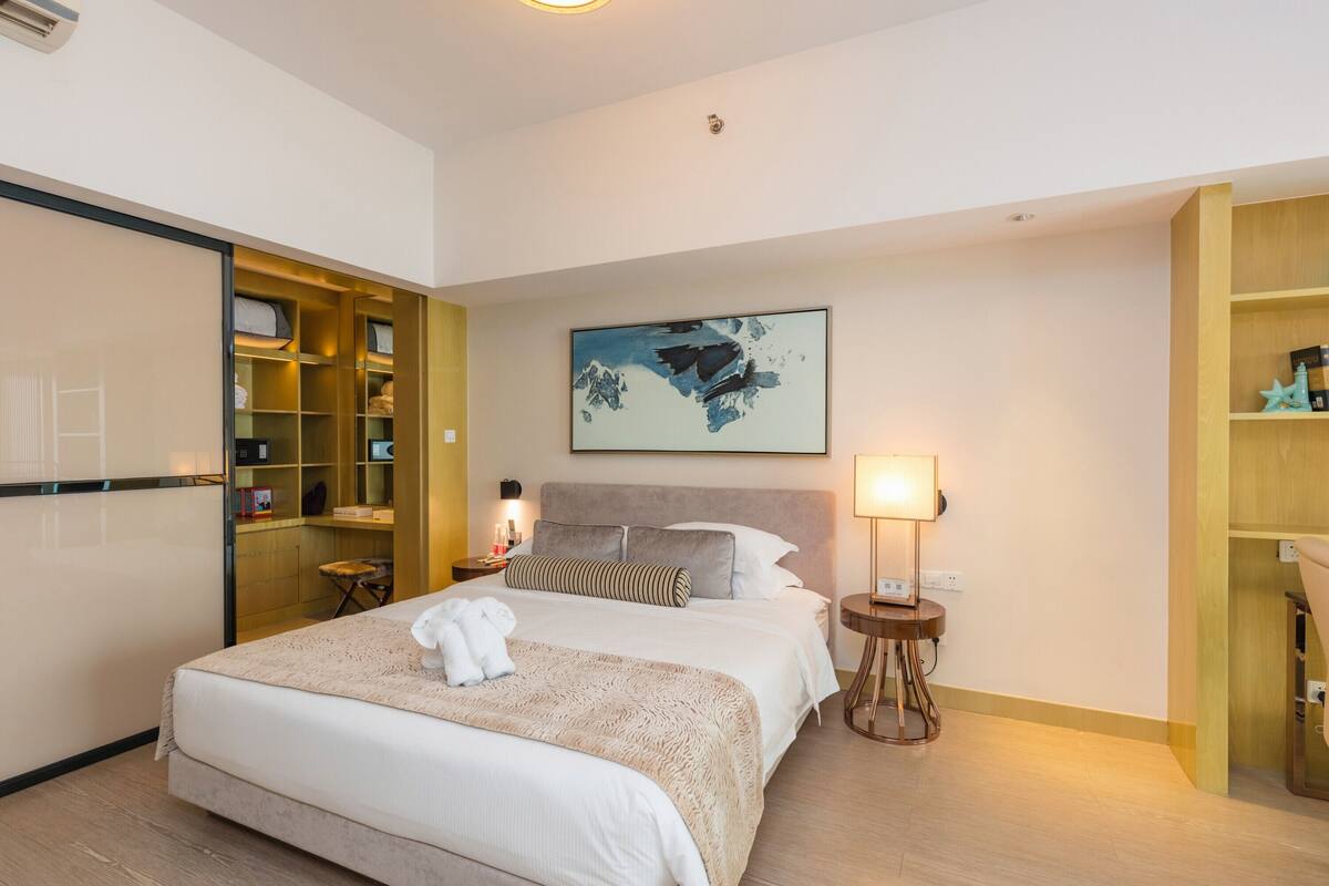 Una habitación de hotel con cama, mesitas de noche, un armario y un cuadro en la pared.