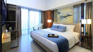 A hotel room with a large bed, a desk with a laptop, a chair, and a TV. - Huafa Exhibition Executive Aparthotel (Zhuhai)