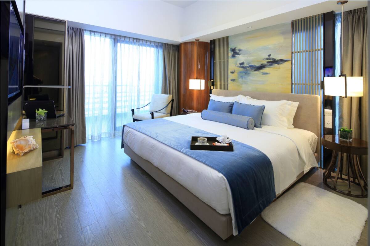 Habitación de hotel con una cama grande, un escritorio con una computadora portátil, una silla y un televisor.