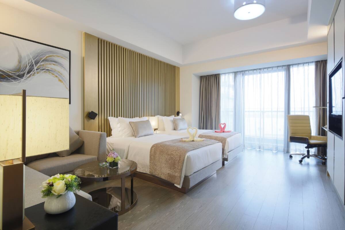 Una habitación de hotel con cama, sofá, escritorio y televisor.