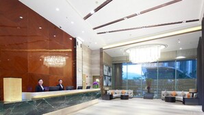 A spacious lobby with a reception desk, seating area, and large windows offering a view of the outdoors. - Huafa Exhibition Executive Aparthotel (Zhuhai)