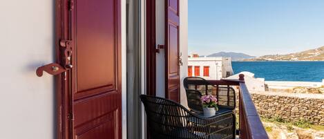 Un balcón con mesa y sillas, con vistas a la costa, edificios y el mar.