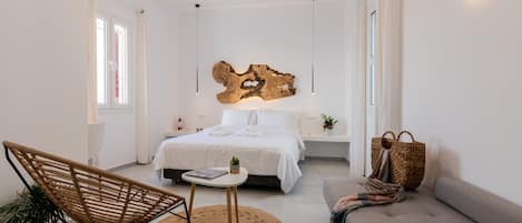 Un dormitorio moderno con cama, sillón, sofá y aplique de pared.